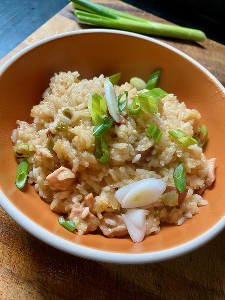 Andouille and Chicken Jambalaya in a bowl on a wooden cutting board 