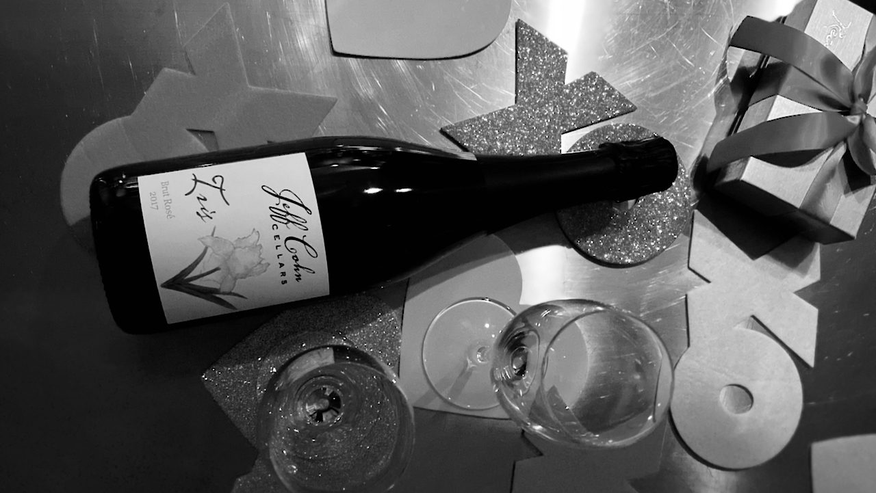 an iris brut rose bottle on its side with a box of truffle chocolates and x's and o's