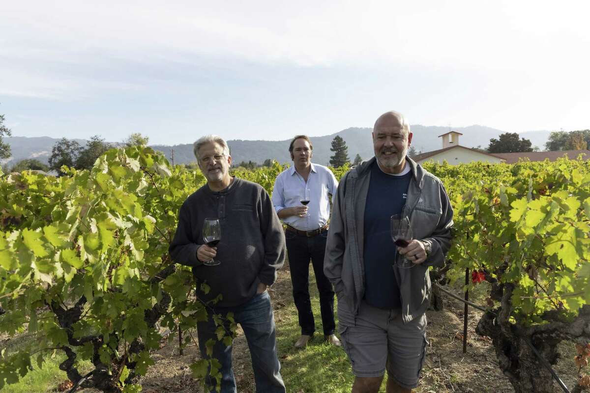 jeff cohn, josh peeples, and russel bevan walking through a vineyard in St. Peter's Church. each holding a glass of wine.